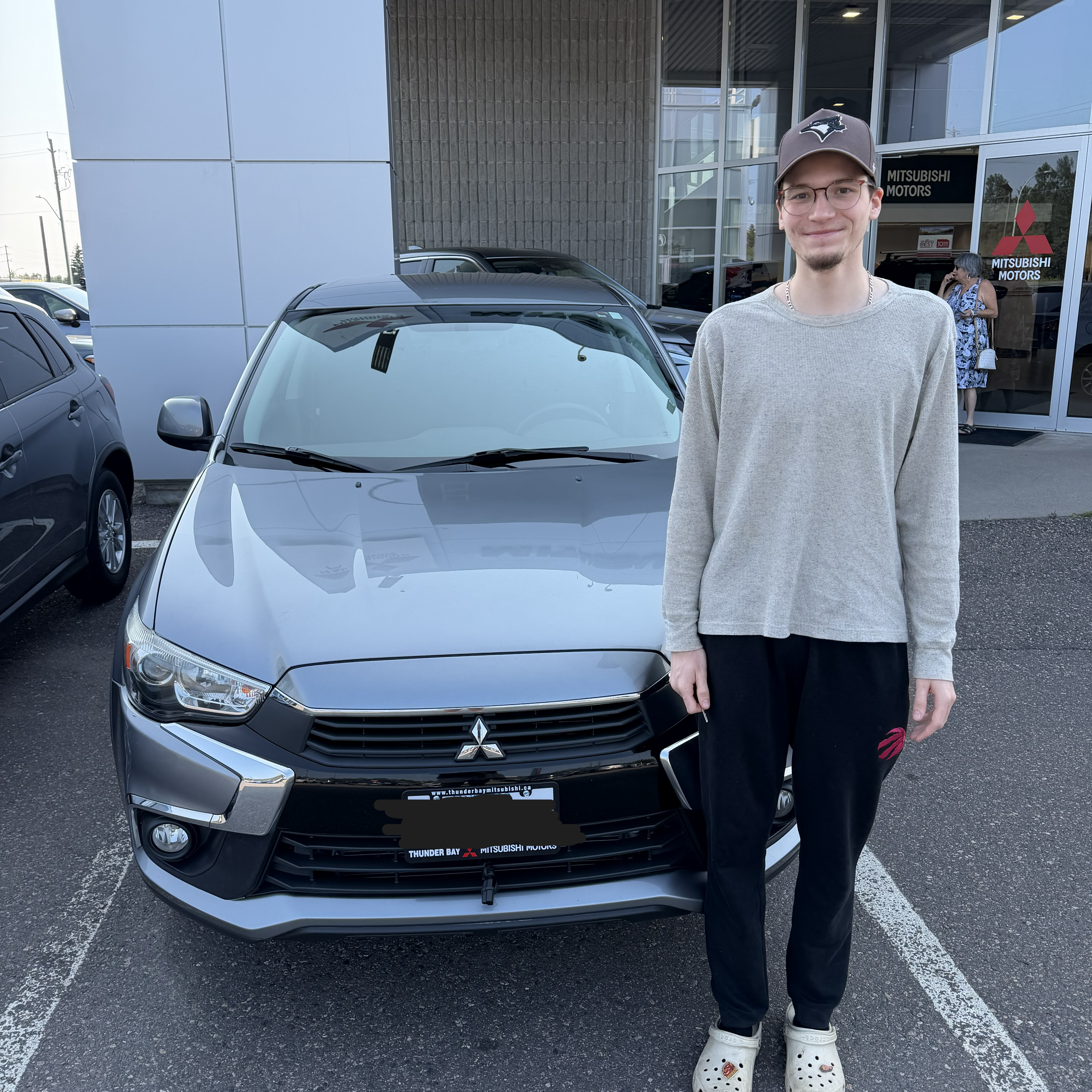A very handsome young man standing in front of his new car!